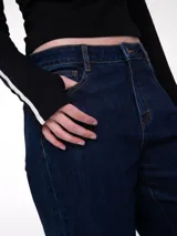 Jeans de corte relajado y tiro medio en color azul índigo. Presenta diseño clásico de cinco bolsillos, cierre de cremallera con botón y puños enrollados en la parte inferior de las piernas.