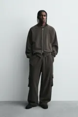 Pantalón cargo de corte relajado con efecto lavado, confeccionado en tejido de algodón. Presenta cintura elástica, bolsillos laterales de plastrón con solapa y bolsillos delanteros.