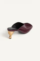 Zapato destalonado tipo mule de piel en color bordó, con escote en pico, punta cuadrada y tacón medio metalizado de diseño escultórico.