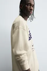 Camiseta de manga larga con cuello redondo, corte relaxed fit y tejido con estructura waffle. Presenta estampados y bordados combinados a contraste en el delantero.