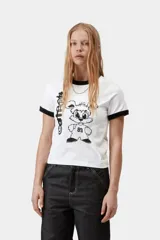 Remera estilo ringer de color blanco con ribetes negros en cuello y mangas, corte ajustado y estampado gráfico delantero de personaje animado.