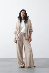 Campera con capucha y cierre frontal, de silueta relajada, hombros caídos y bolsillos laterales. Presenta terminaciones elastizadas en puños y ruedo, con líneas de recorte frontales y cierre metálico con tirador circular.