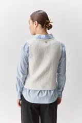 Chaleco de tejido en relieve color blanco, con escote en V y cierre frontal mediante lazos.