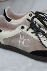Championes de estilo urbano en combinación de tonos marrones y crema, confeccionados en gamuza y cuero. Presentan cordones jaspeados, suela de goma y detalle de logo bordado en el lateral.