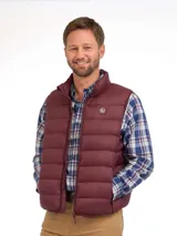 Chaleco acolchado tipo puffer color bordó, con cierre frontal y cuello alto. Presenta un diseño de costuras horizontales y logo circular en el pecho.