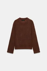 Jersey de manga larga color marrón oscuro, confeccionado en tejido de punto con calados que le otorgan transparencia. Presenta cuello redondo y acabados en rib en puños, cuello y bajo.