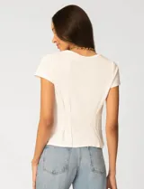 Remera blanca de manga corta con cuello redondo, confeccionada en una mezcla de modal, poliéster y elastano. Presenta un diseño con alforzas verticales en el frente que aportan estructura y una silueta relajada.