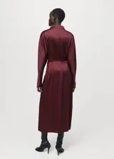 Vestido midi de tejido satinado en color bordó, de corte recto con manga larga, cuello alto y abertura en el bajo delantero. Incluye un cinturón ajustable delgado con detalle metálico dorado.