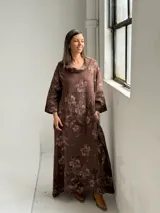 Vestido largo marrón de lino con estampado floral, cuello redondo holgado y mangas tres cuartos.