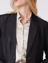 Blazer de corte sastrero confeccionado en tejido con apariencia denim, de silueta entallada. Presenta cuello con solapa, cierre frontal de un solo botón, bolsillos de ojal laterales y forro interno.