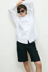 Camisa blanca de corte oversize, con cuello clásico, cierre frontal con botones y mangas largas.