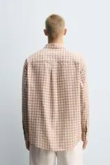 Camisa de corte relajado confeccionada en tejido fluido con algodón. Presenta un diseño de cuadros, cuello solapa, manga larga con puño abotonado, bolsillo plastrón en el pecho y cierre frontal con botones.
