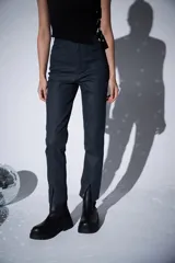 Pantalon de jean engomado color gris oscuro, de corte slim fit y tiro alto. Presenta costuras verticales frontales y aberturas en el ruedo.