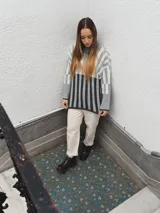 Sweater tejido a rayas horizontales color beige, marrón y negro, de cuello alto y corte holgado.