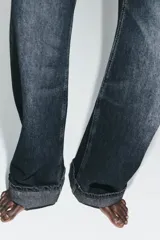 Jeans de tiro medio con corte baggy, cinco bolsillos y bajo con dobladillo. Cierre frontal con cremallera y botón metálico.