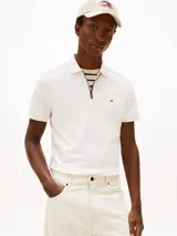 Chomba de corte regular de Tommy Hilfiger, color blanco, con cuello polo y cierre de cremallera de 1/4. Cuenta con mangas cortas y detalle del logo bordado en el pecho.