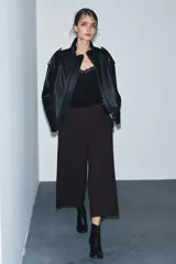 Pantalón de tiro medio confeccionado en viscosa, con corte recto y largo tobillero. Presenta cintura con trabillas, bolsillos laterales y bolsillos de vivo en la parte trasera. Cierre frontal mediante cremallera, botón y ganchos metálicos.