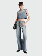 Top de denim celeste con diseño acolchado en patrón de rombos, de corte crop y sin mangas. Presenta un diseño de doble botonadura con botones dorados grabados, cuello redondo y detalles de charreteras en los hombros.