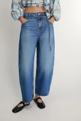 Jeans de tiro medio con diseño barrel, cinco bolsillos y cinturón fino del mismo tejido. Presenta pernera ancha en los muslos que se estrecha gradualmente hacia el tobillo, con cierre frontal de cremallera y botón.