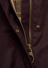 Parka color bordó, de corte recto, con cierre frontal de cremallera y botones a presión. Presenta cuello camisero de pana, bolsillos frontales de parche con solapa y mangas largas con puños ajustables. Incluye forro interior.