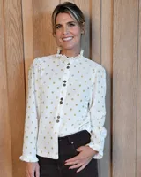 Camisa de manga larga con estampado a cuadros en tonos verde oscuro y beige. Presenta cuello alto con volados, cierre frontal con botones y puños con volados elásticos.