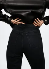 Jeans mom-fit de tiro alto color negro, confeccionados en mezcla de algodón y elastano con diseño de cinco bolsillos, trabillas y cierre frontal de cremallera y botón.