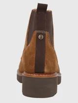 Bota de gamuza color tostado con cordones frontales y paneles elásticos laterales. Presenta una suela de goma gruesa con costuras decorativas, ojales metálicos y tirador trasero para facilitar el calce.