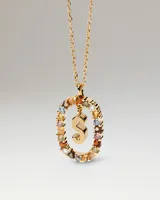 Collar de plata dorada con cadena de eslabones y un dije colgante en forma de letra 'S' dentro de un aro ovalado decorado con cristales multicolor.