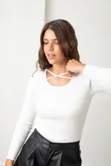 Polera de morley blanco con cuello redondo y detalle de tiras cruzadas en el escote, de manga larga y ajuste al cuerpo.