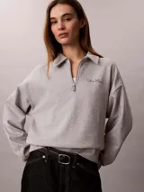Buzo gris melange de french terry, con cuello tipo polo de media cremallera y manga larga. Presenta el logo de Calvin Klein bordado en el pecho.