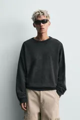 Sudadera de corte relaxed fit confeccionada en tejido de algodón con interior de rizo. Presenta cuello redondo, manga larga y acabados en rib, con un acabado de efecto lavado que le otorga una apariencia única.