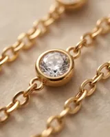 Pulsera de acero con baño de oro y dijes circulares con circonias engastadas.