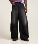 Pantalón de jeans estilo barrel color negro con efecto acid wash, tiro medio, cierre frontal con botón y cremallera, bolsillos, recortes laterales y pinzas en las rodillas.