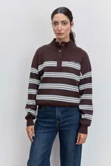 Sweater de punto con diseño a rayas horizontales en azul marino, blanco y bordó. Presenta cuello alto con cierre de botones a presión, mangas largas con puños acanalados y un pequeño bordado en el pecho.