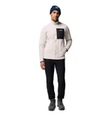 Campera de polar tipo sherpa en color beige, con cierre frontal completo y cuello alto. Presenta un bolsillo frontal en el pecho con cierre y revestimiento en contraste negro, además de bolsillos laterales. Incluye el logo de la marca en el bolsillo del pecho.
