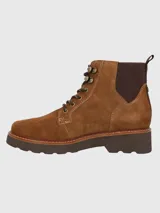 Bota acordonada de gamuza color marrón, con suela de plataforma dentada y paneles laterales elásticos. Presenta ojales metálicos y cordones bicolor.