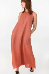 Vestido midi verde de lino italiano, con diseño sin mangas, cuello redondo y estampado de líneas onduladas punteadas. Cuenta con bolsillos laterales.