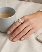 Anillo de acero con diseño de hebilla cuadrada que incluye incrustaciones de nácar y circonias en la banda.