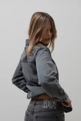 Chaqueta de denim de algodón con corte entallado en la cintura, cuello clásico, cierre frontal con botones metálicos y dos bolsillos con solapa en el pecho.