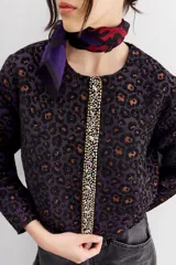Campera bomber corta a la cintura con cuello redondo, confeccionada en jacquard con estampado de leopardo en tonos morados y marrones. Presenta una cartera frontal con cierre adornada con piedras y strass.
