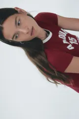 Remera de algodón color bordó con cuello redondo en contraste blanco y estampa frontal con la frase 'AMOUR 15 PARIS' en letras blancas.