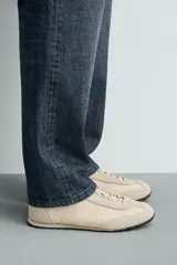 Zapatilla de cordones fabricada en piel con acabado serraje y combinación de piezas de tejido, con suela dentada en contraste de color y pespuntes decorativos.
