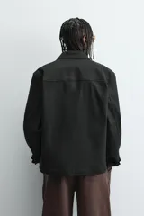 Cazadora azul marino de corte regular fit, confeccionada en tejido técnico repelente al agua. Presenta cuello subido, manga larga, bolsillos de vivo en cadera, bolsillo interior y acabados en rib en puños y bajo. Cierre frontal de cremallera oculta por solapa con botones a presión.