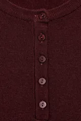 Jersey de punto de manga larga y cuello redondo con cierre frontal de botones. Presenta un diseño de rayas horizontales en tonos marrones, negros, blancos y azules.