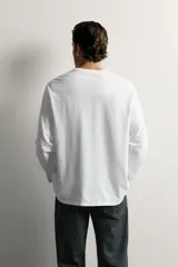 Remera manga larga blanca de corte relaxed fit, con cuello redondo y diseño liso de algodón.