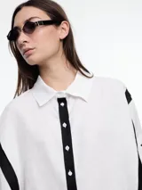 Camisa de lino roja con silueta amplia y mangas 3/4. Diseño con tiras de color rosa en contraste en la cartera, mangas y cuerpo. Tiene tajos laterales y ruedo irregular en el frente.