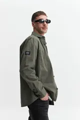 Sobrecamisa verde militar de twill de algodón, con cuello clásico, cierre frontal con botones a tono, dos bolsillos tipo parche con solapa abotonada en el pecho, mangas largas con puños abotonados y corte recto.