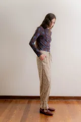 Pantalón de corte relajado confeccionado en pana color beige con estampado floral pequeño. Presenta cintura elástica en la parte posterior con cordón ajustable, bolsillos laterales y terminación en los tobillos con detalle de frunce ajustable.