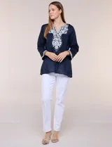 Blusa de corte holgado de inspiración étnica con bordados ornamentales blancos a contraste. Presenta escote en V pronunciado con pechera bordada con motivos arabescos y florales, mangas largas y aberturas laterales en el ruedo.