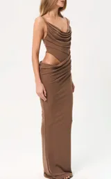 Vestido largo color marrón, de corte ajustado, con escote drapeado y tirantes finos. Presenta un diseño con abertura lateral en la cintura y detalle de fruncido en la falda.